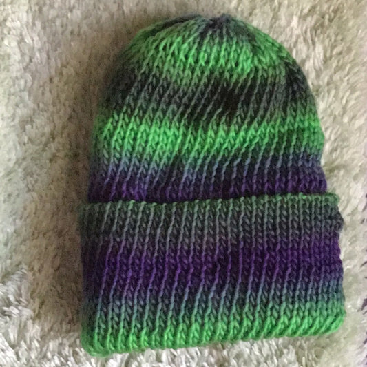Knit Beanie with shades of green blended with purple, in a striped pattern.